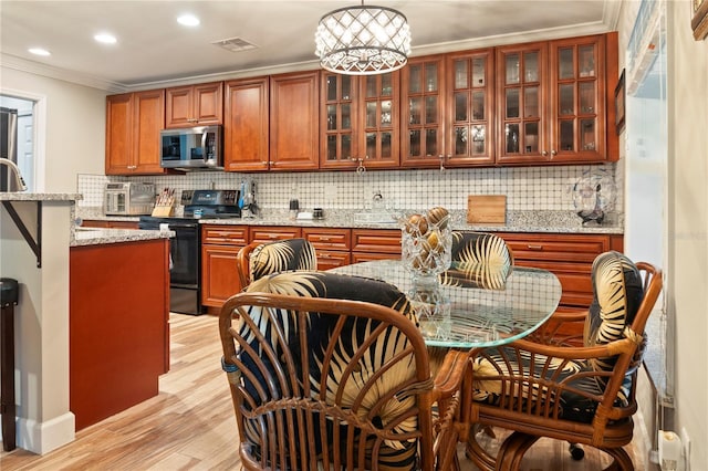 kitchen featuring black electric range oven, light wood-style flooring, stainless steel microwave, visible vents, and ornamental molding