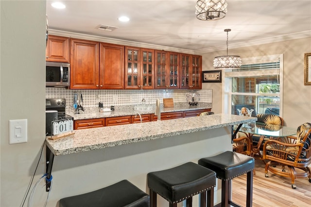 kitchen featuring a kitchen breakfast bar, backsplash, black electric range oven, brown cabinets, and stainless steel microwave