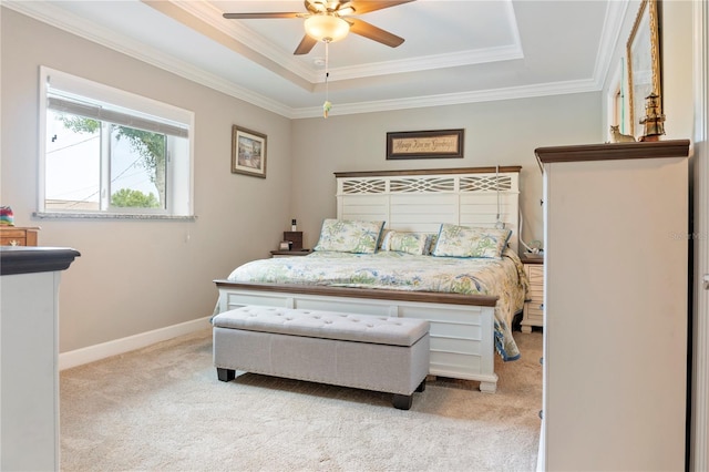 carpeted bedroom with crown molding, baseboards, ceiling fan, and a tray ceiling