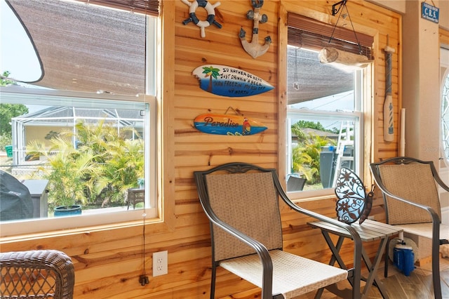 living area featuring wood finished floors, wooden walls, and a healthy amount of sunlight