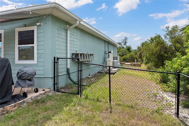 view of side of home with a lawn, a gate, and fence