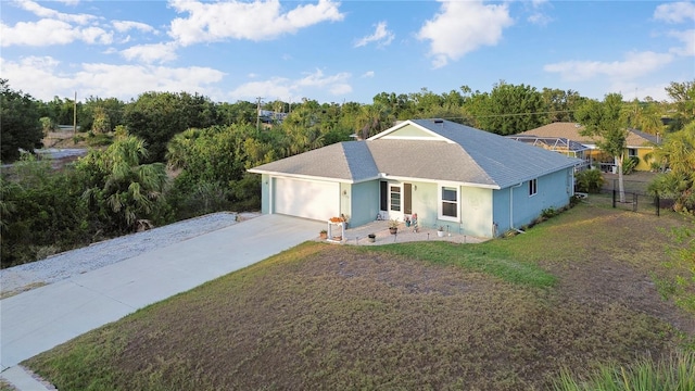 ranch-style house with fence, a shingled roof, a front lawn, a garage, and concrete driveway