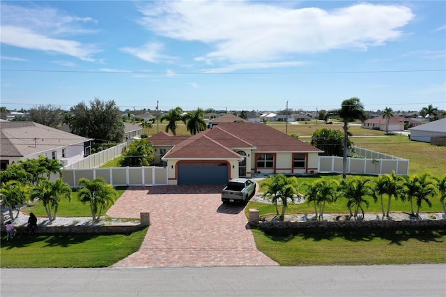 mediterranean / spanish home with a front yard, a residential view, decorative driveway, an attached garage, and fence