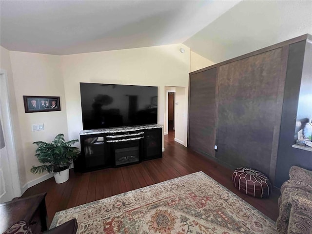 living area with dark wood-style flooring, vaulted ceiling, and baseboards