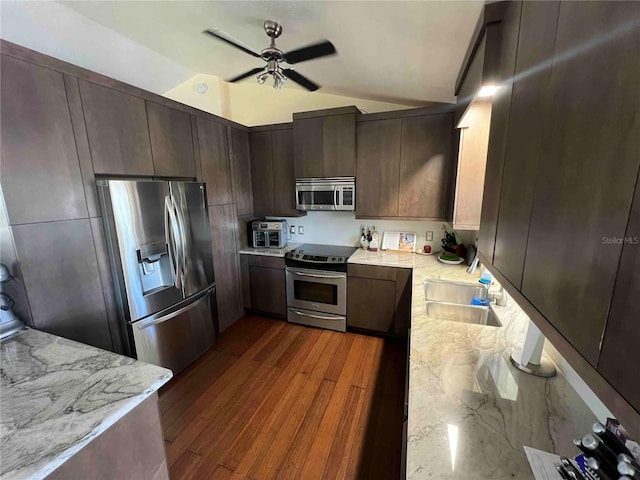 kitchen featuring a sink, appliances with stainless steel finishes, dark brown cabinets, vaulted ceiling, and a ceiling fan