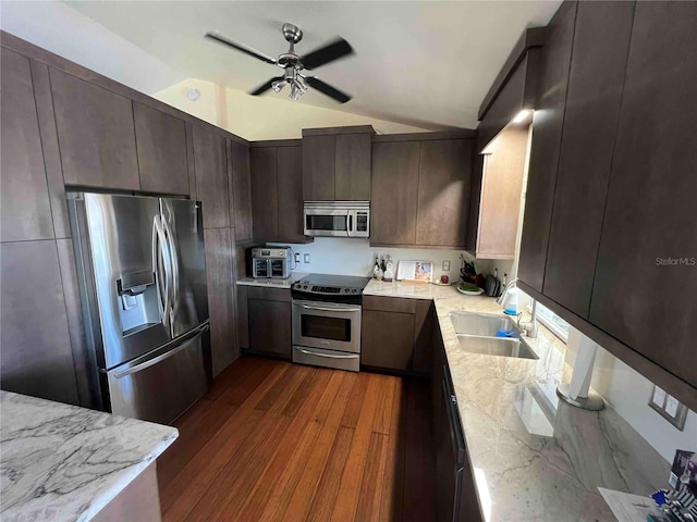 kitchen with a sink, ceiling fan, dark wood-type flooring, appliances with stainless steel finishes, and lofted ceiling