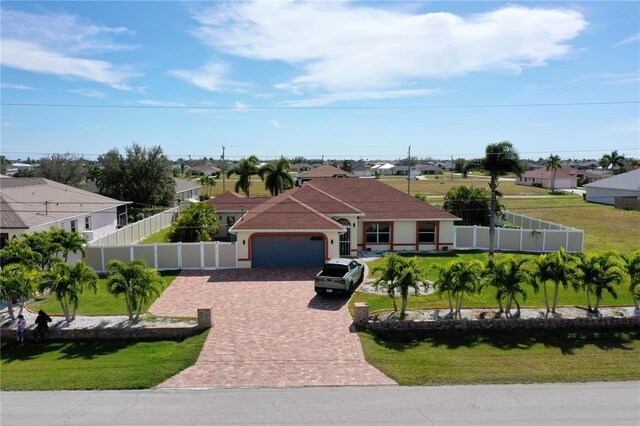 mediterranean / spanish-style home featuring a residential view, decorative driveway, fence private yard, and a garage