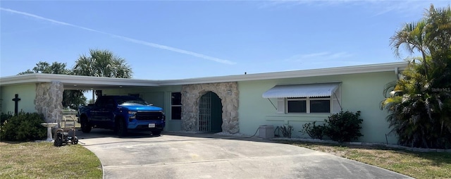 ranch-style house with a carport, stucco siding, driveway, and stone siding