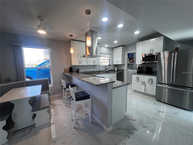 kitchen featuring marble finish floor, dark stone countertops, stainless steel appliances, a peninsula, and island range hood