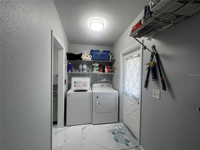 laundry area with a textured wall, laundry area, independent washer and dryer, and marble finish floor