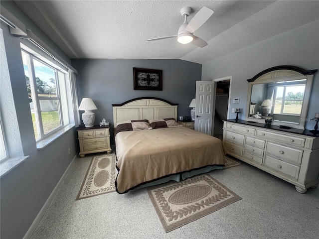 bedroom featuring baseboards, a ceiling fan, vaulted ceiling, and a textured ceiling