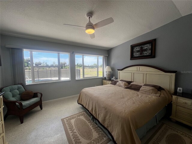 bedroom with multiple windows, carpet, a ceiling fan, and a textured ceiling