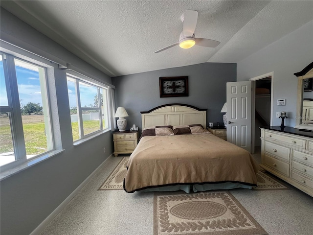 bedroom featuring baseboards, a ceiling fan, a textured ceiling, and lofted ceiling