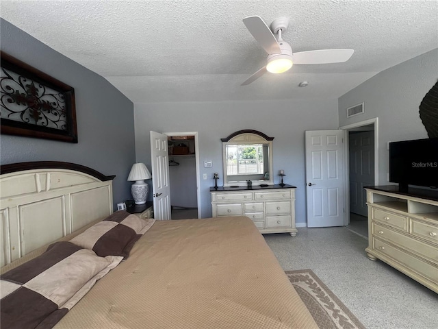 bedroom featuring visible vents, lofted ceiling, a textured ceiling, a spacious closet, and a ceiling fan