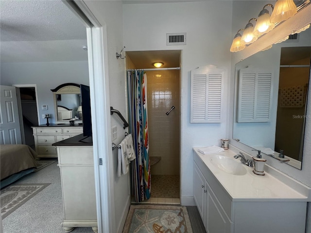 ensuite bathroom with connected bathroom, visible vents, tiled shower, and vanity