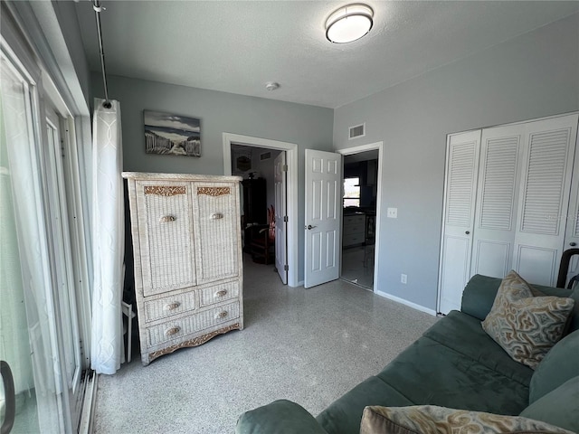 living area with baseboards, a textured ceiling, speckled floor, and visible vents