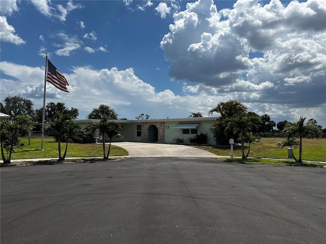 ranch-style home with stucco siding, driveway, and a front yard