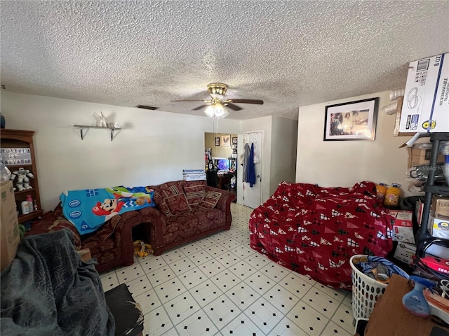 living area with a textured ceiling, ceiling fan, tile patterned floors, and visible vents