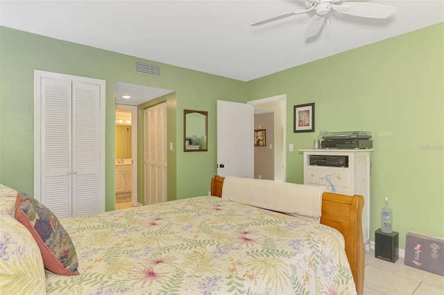 bedroom featuring light tile patterned floors, ensuite bath, and a ceiling fan