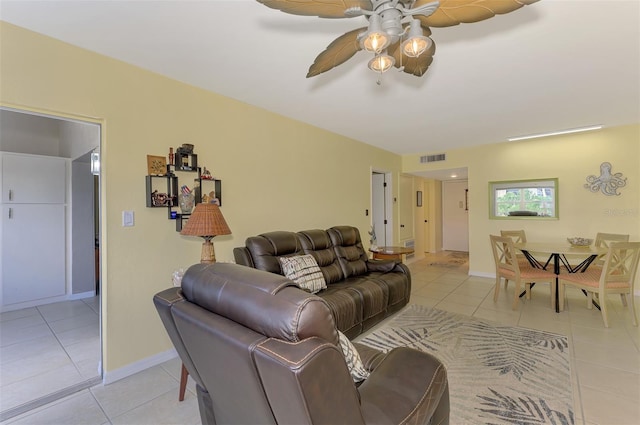 living area with light tile patterned floors, ceiling fan, and baseboards