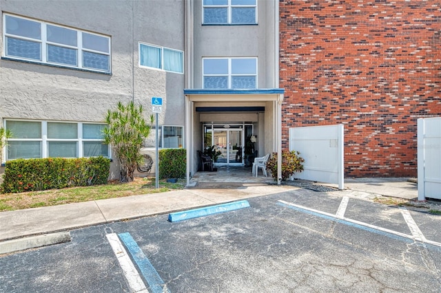 property entrance with uncovered parking, brick siding, and stucco siding