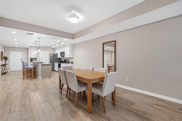 dining space with light wood-style flooring, baseboards, and recessed lighting
