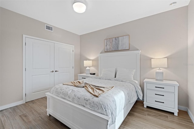 bedroom with light wood-style floors, baseboards, and a closet