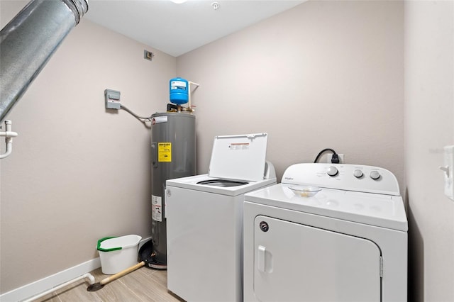 washroom featuring water heater, washer and clothes dryer, light wood-style floors, and baseboards