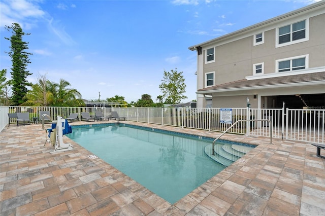 community pool with a patio area and fence
