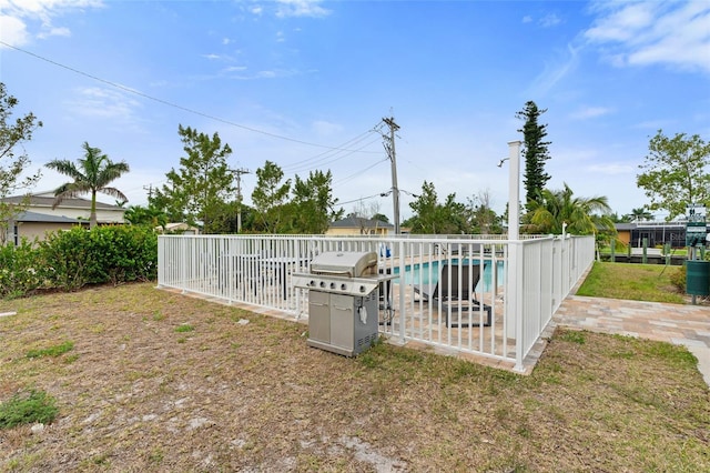 view of pool with area for grilling, fence, and a patio area