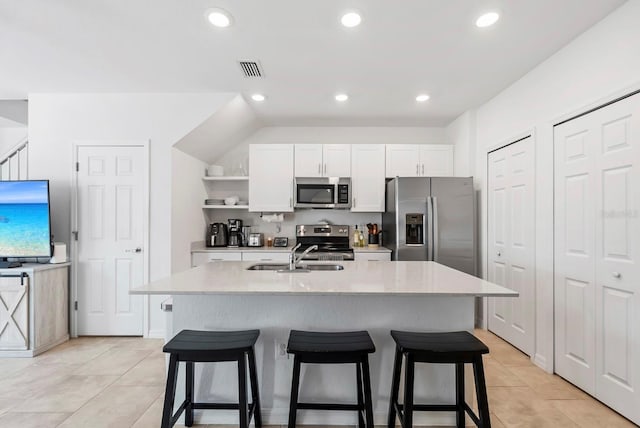 kitchen with a sink, a kitchen breakfast bar, white cabinets, and stainless steel appliances