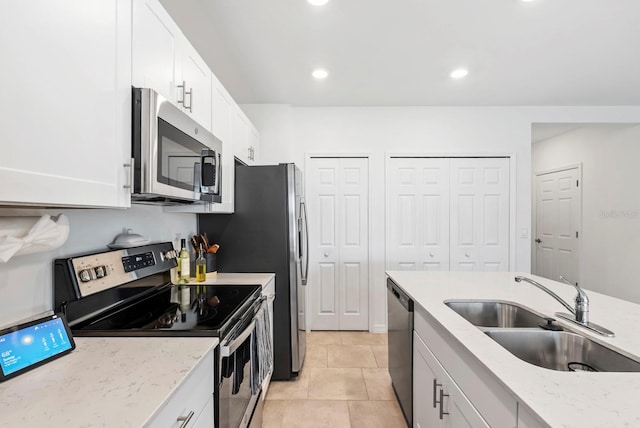 kitchen featuring white cabinets, light stone counters, a sink, stainless steel appliances, and recessed lighting