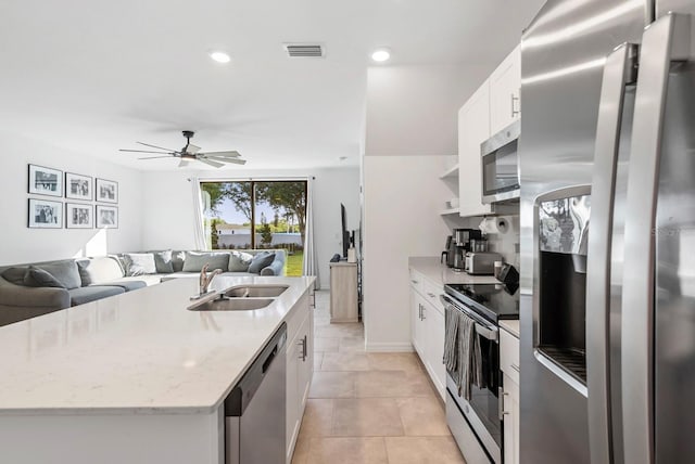 kitchen with ceiling fan, a kitchen island with sink, visible vents, a sink, and stainless steel appliances