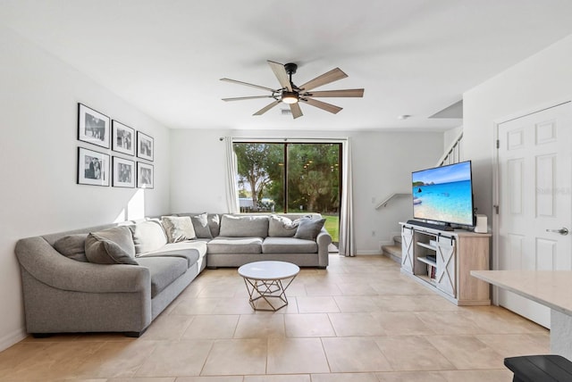 living area featuring light tile patterned flooring, ceiling fan, and baseboards