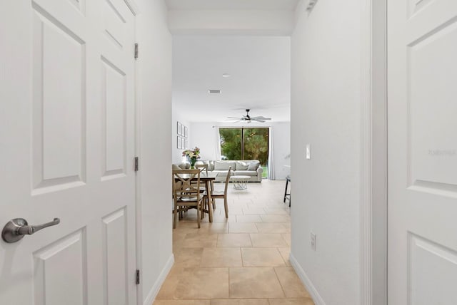 hallway featuring visible vents, baseboards, and light tile patterned flooring