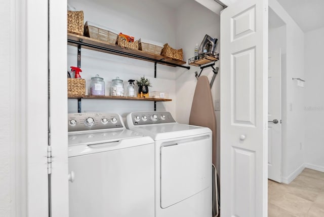 clothes washing area with laundry area, baseboards, and washer and dryer