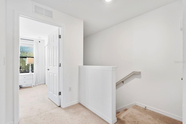 corridor featuring baseboards, an upstairs landing, carpet, and visible vents