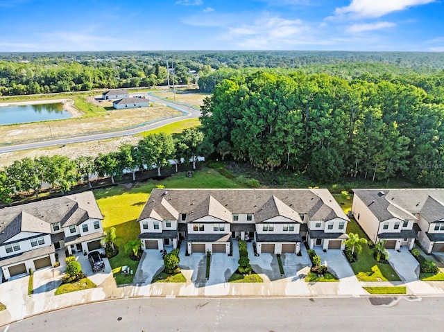 drone / aerial view featuring a water view, a view of trees, and a residential view