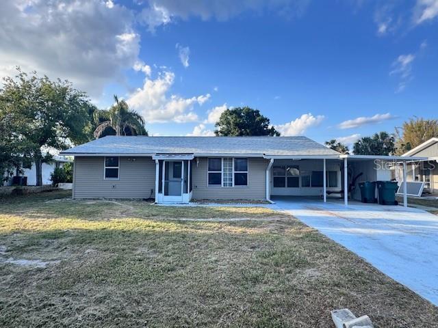ranch-style home featuring driveway, a carport, and a front lawn