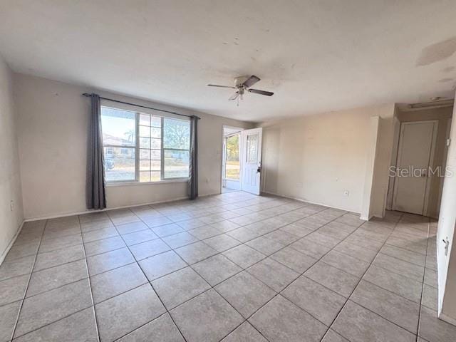 unfurnished room with light tile patterned floors, ceiling fan, and baseboards