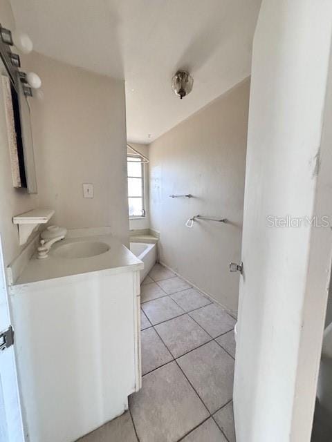 bathroom featuring tile patterned floors, a tub to relax in, and vanity