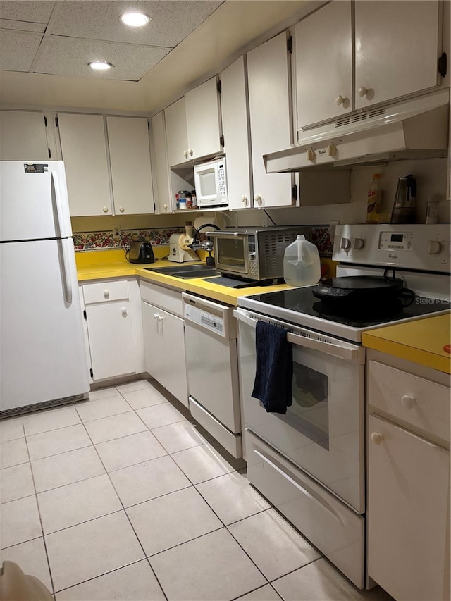 618 Bird Bay Dr S Unit 109, Venice, FL 34285 - kitchen featuring white appliances, under cabinet range hood, light countertops, light tile patterned floors, and a sink