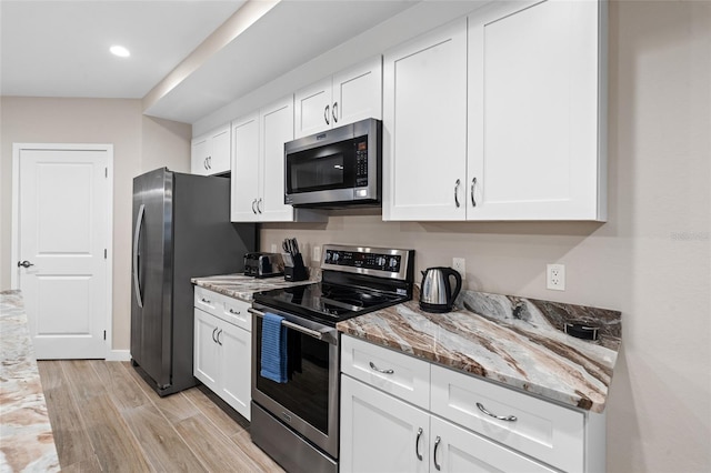 kitchen featuring appliances with stainless steel finishes, light wood-type flooring, light stone counters, white cabinets, and recessed lighting