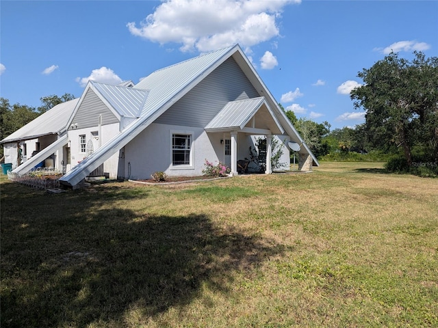 back of property with stucco siding, a yard, and metal roof