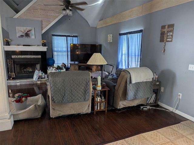living room featuring a ceiling fan, a tiled fireplace, wood finished floors, baseboards, and lofted ceiling