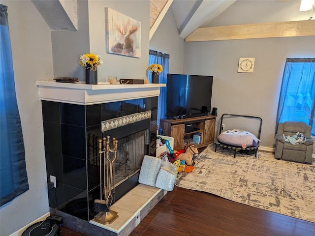 living room featuring baseboards, lofted ceiling, wood finished floors, and a tile fireplace