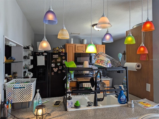 kitchen featuring visible vents, black appliances, a textured ceiling, and decorative light fixtures