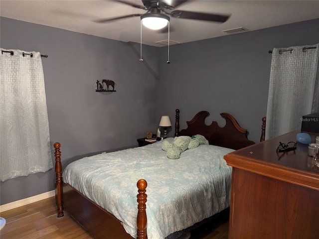 bedroom featuring ceiling fan, baseboards, visible vents, and wood finished floors