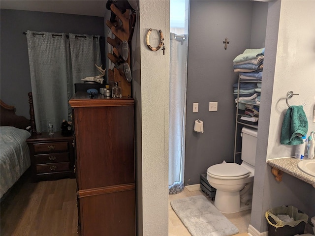 bathroom featuring wood finished floors and toilet