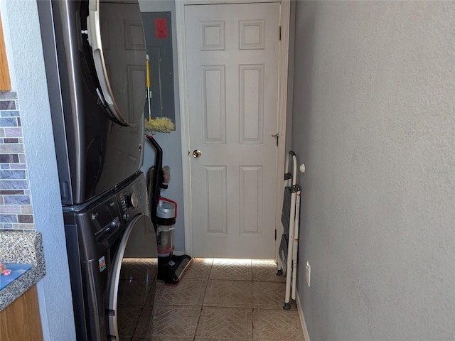 laundry area with baseboards and stacked washing maching and dryer